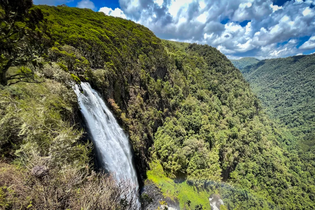Waterfall cascading down lush green mountainside in Aberdares National Park. Hiking Mount Kenya and the Aberdares.