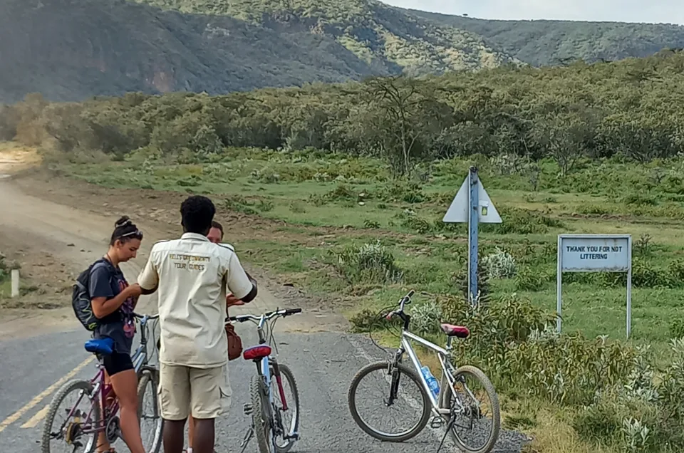 Tourists with bicycles and a local guide at Hell’s Gate National Park in Naivasha, Kenya, surrounded by scenic hills and open savannah