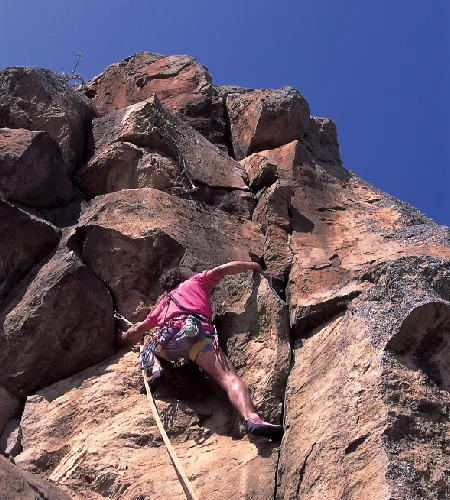 Woman climbing a rocky cliff at Hell’s Gate National Park in Naivasha, Kenya, surrounded by dramatic gorges and scenic landscapes